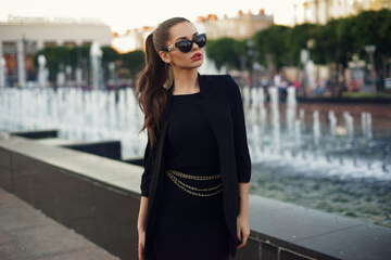 Donna elegante vestita di nero con occhiali e borsetta