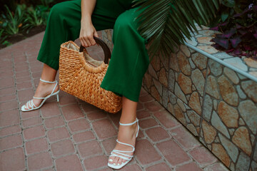 donna con sandali bianchi e pantaloni verdi, borsa a paglia