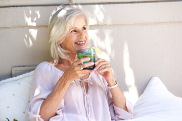 donna over 50 nel camicia bianca e beve limonata
