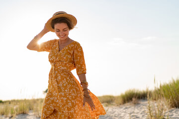 donna nella spiaggia, indossando il vestito estivo lungo a fiori e cappello da paglia