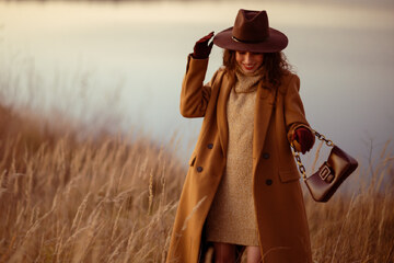 donna nel vestito in maglia beige e cappotto marrone