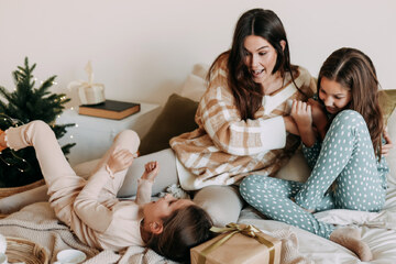 madre con le due figlie a letto nei loro pigiami, durante il Natale