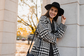 donna sorridente con cappotto a motivi bianchi e neri e cappello nero