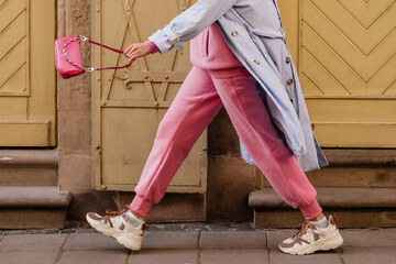 donna nel tuta di ginnastica rosa con borsa rosa e trench grigio