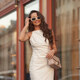 donna nel vestito da sero bianco con gli occhiali da sole