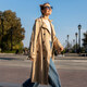donna nel parco indossando il trench beige, jeans e maglietta bianca