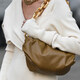 donna in vestito bianco in maglia porta una borsa marrone sulla spalla, la borsa ha una catena d'oro