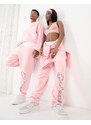 ASOS DESIGN - Joggers comodi unisex lavaggio rosa con stampa in coordinato